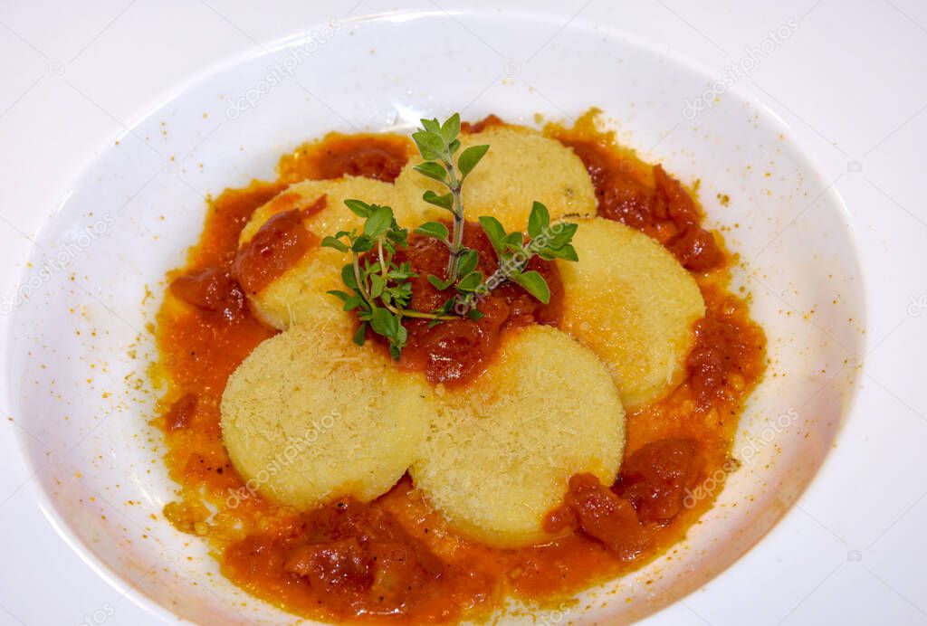 Gnocchi alla Romana with tomato sauce and cheese , typical Italian dumplings of Rome made with semolina