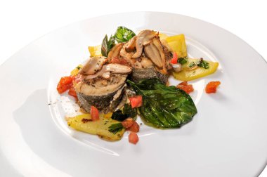 Porcini mantarlı fırınlanmış yılan balığı (Boletus edulis), patates, domates ve fesleğen yaprağı Binco 'da izole edilmiş beyaz tabakta, kapat.
