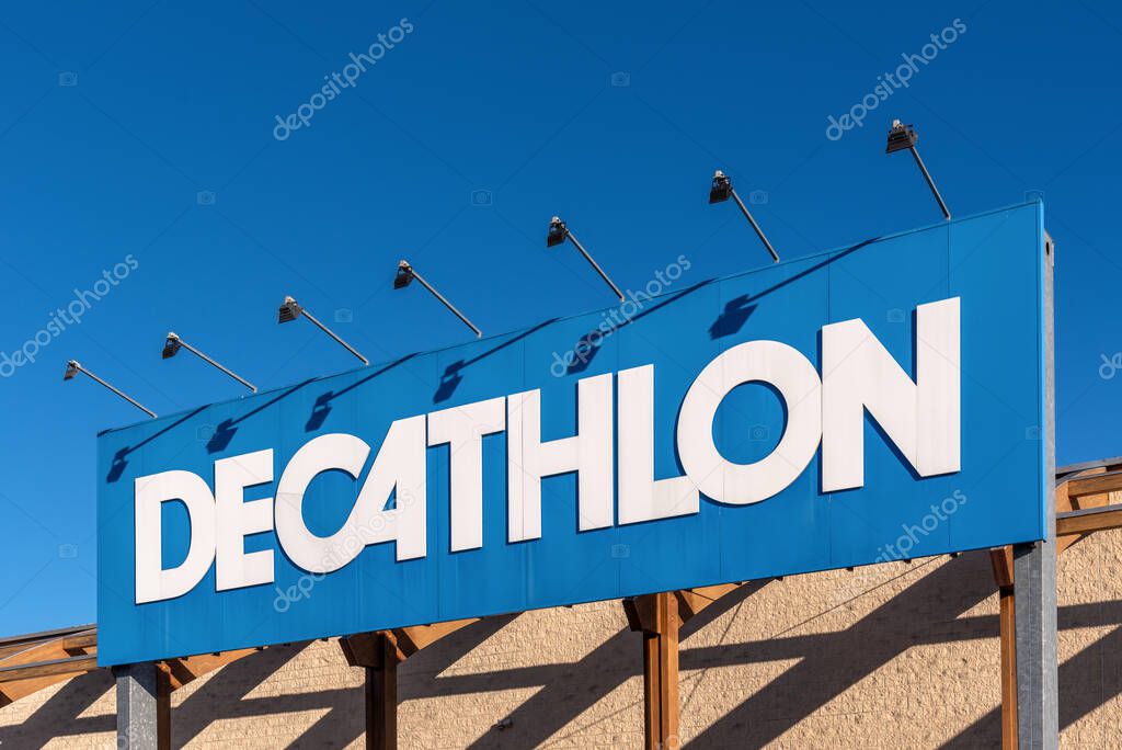 Turin, Italy - December 6, 2021: Decathlon logo on sign at entrance store on blue sky, Decathlon is largest sporting goods retailer in the world
