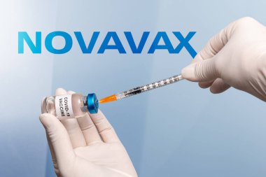 Torino, İtalya - 18 Aralık 2021: Arka planda Novavax Laboratuvarı logosu, protein aşısı, aşı konsepti olan şırıngalı lateks eldivenli hemşire elleri