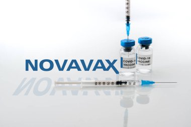 Torino, İtalya - 18 Aralık 2021: Arka planda Novavax Laboratuvarı logosu, protein aşısı, aşı konsepti olan covid-19 aşısı şişeleri