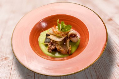 Bezelye kremalı balık güveci - karides, turbot, mürekkep balığı ve mürekkep balığı ahşap masadaki toprak kapta.