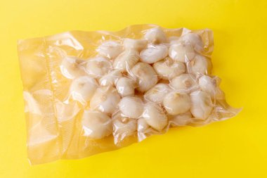 Küçük düz soğanlar (İtalya 'da borettan soğanı olarak adlandırılır) sarı zemin üzerinde izole edilmiş vide pişirmek için paketlenmiş vakum içinde