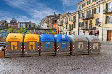 Cuneo, İtalya - 11 Nisan 2022: Tarihi merkezdeki Boves Meydanı 'nda seçici atık toplama kutuları sırası. Kağıt için sarı, plastik için mavi, kuru atık için gri