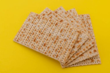 Hamursuz Bayramı 'nda Pesach için mayasız Matzo ekmeği. Matzah düz ekmekleri sarı arkaplanda izole edilmiş.