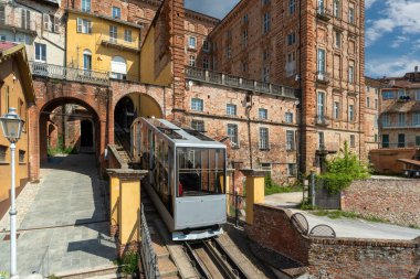 Mondovi, Italy - April 29, 2022: Funicular train arriving at top station of rione Piazza with ancient buildings, the funicular connects the Breo district in valley and the Piazza district upstream