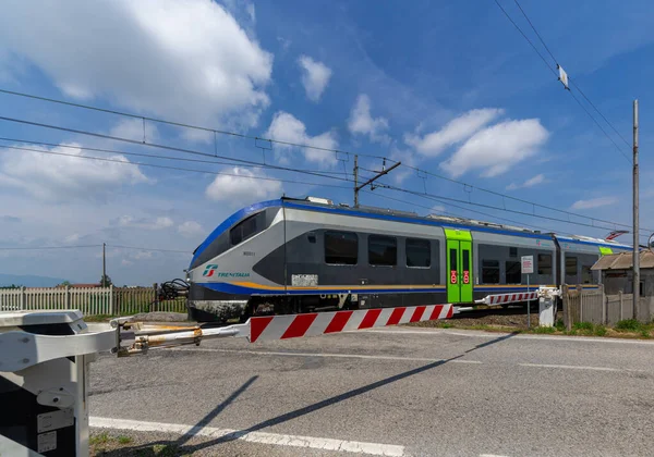 Centallo, Cuneo, İtalya - 13 Mayıs 2022: Torino - Cuneo demiryolu hattındaki Trenitalia treninin geçişi ile kapalı seviye geçiş