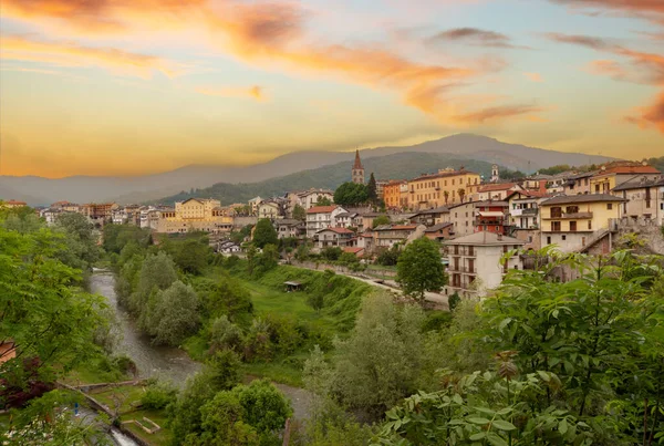Dronero, Piedmont, İtalya: Maira Vadisi 'ndeki Maira nehri manzaralı eski köy. Renkli bulutlu gün batımı gökyüzü manzarası