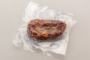 İtalyan soppressata calabrese salam vakum kapalı sous vide pişirme için kapalı üst görünüm Gri arka plan izole.