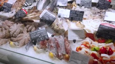 Fossano, Italy - July 21, 2022: Showcase of the Fish section at the supermarket. Fresh and defrosted fish on ice with price tags and fish origin for sale in the shop window in an Italian supermarket