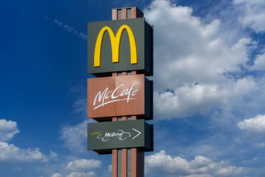 Savigliano, İtalya - 16 Haziran 2022: McDonald 's tabelası üzerinde McCafe ve McDrive logosu olan beyaz bulutlu mavi gökyüzü. McDonald 's Corporation dünyanın en büyük hamburger fast food restoranı zinciri.