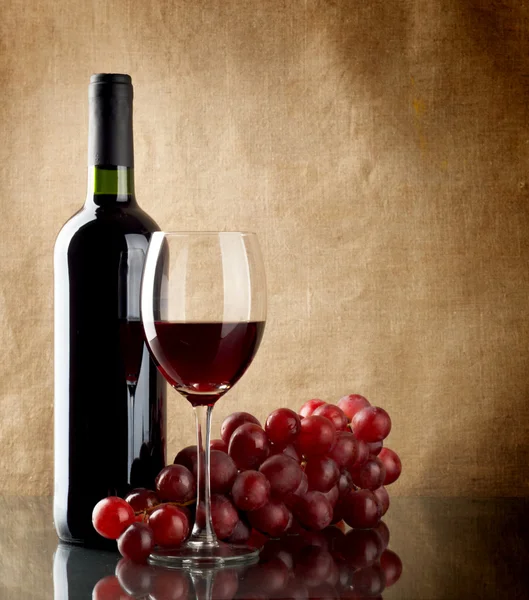 Flasche Wein und ein Bund roter Trauben — Stockfoto