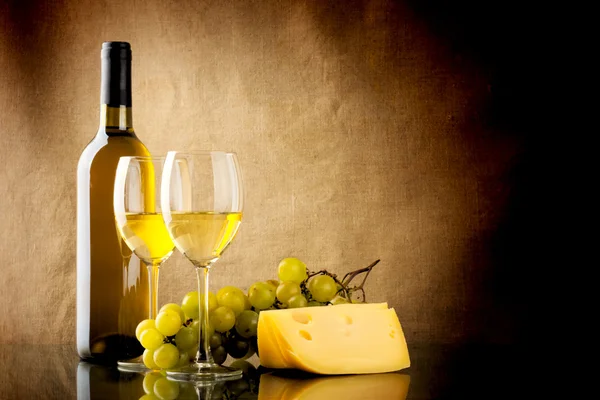 Fles wijn, een bos van witte druiven en een stuk kaas — Stockfoto