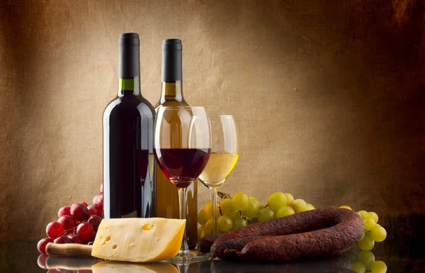 Vin, druer, ost og pølser på lerretsbakgrunn – stockfoto