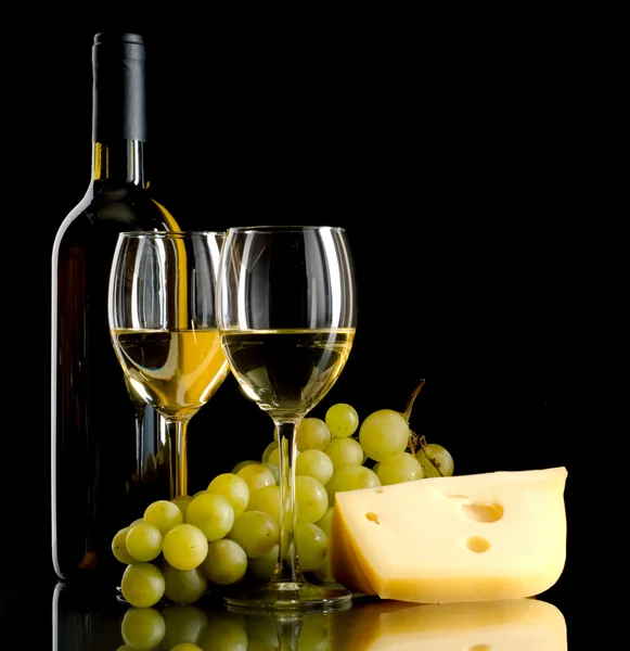 Garrafa de vinho, um monte de uvas brancas e um pedaço de queijo — Fotografia de Stock
