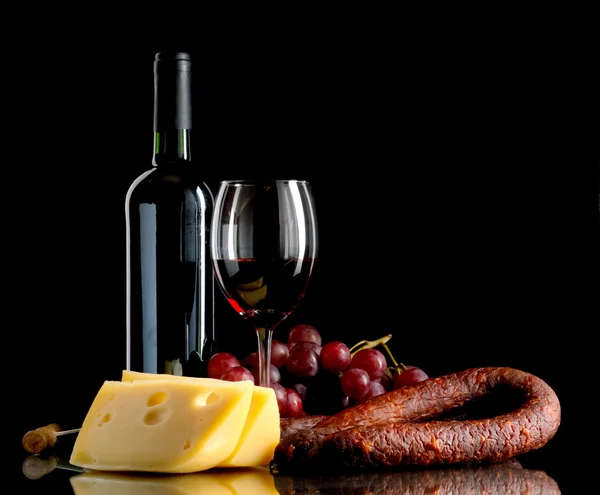 Vin, raisins, fromage et saucisse sur fond noir — Photo