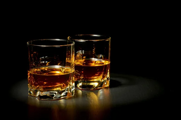 Two glasses of whiskey on black table — Stock Photo, Image