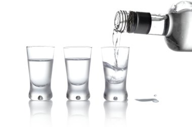 Bottle and glasses of vodka poured into a glass isolated on whit clipart
