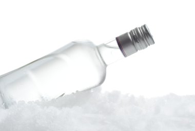 Bottle of vodka lying on ice on white background clipart