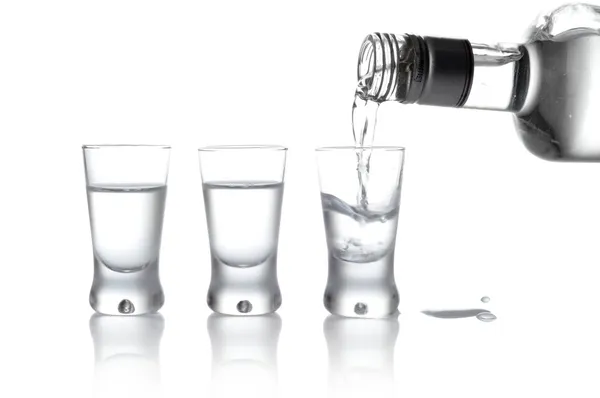 Flaska och glas vodka hälls i ett glas isolerade på whit — Stockfoto