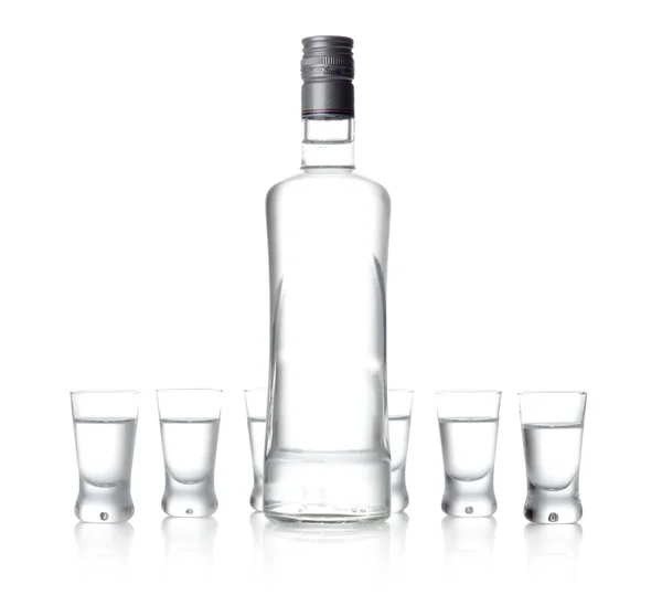 Garrafa e copos de vodka de pé isolados sobre fundo branco — Fotografia de Stock