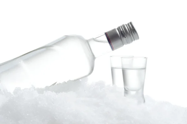 Bottle and glasses of vodka lying on ice on white background — Stock Photo, Image