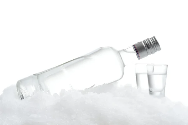 Bottle and glasses of vodka lying on ice on white background — Stock Photo, Image