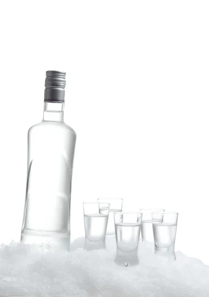 Garrafa de vodka com óculos em pé no gelo sobre fundo branco — Fotografia de Stock