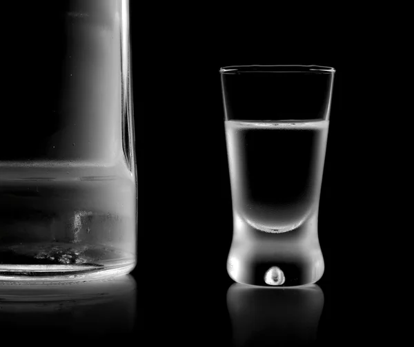 Bottle and glass of vodka standing isolated on black background — Stock Photo, Image