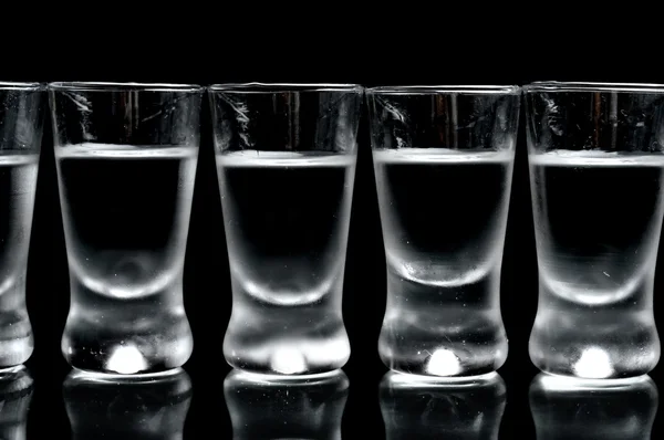 Viele Gläser Wodka isoliert auf schwarzem Hintergrund — Stockfoto