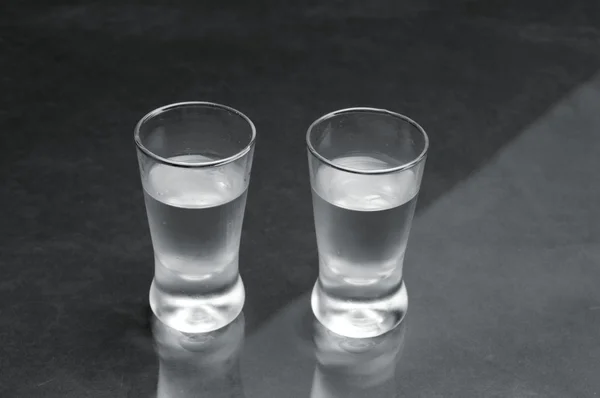 Two glasses of vodka on black marble table — Stock Photo, Image