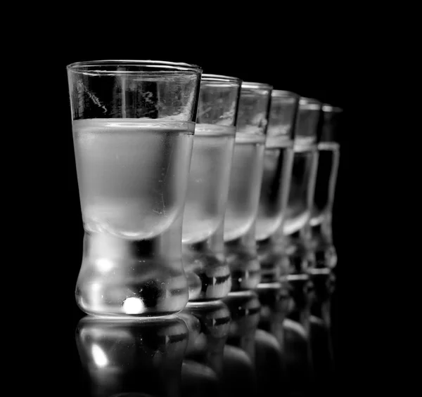 Many glasses of vodka isolated on black background — Stock Photo, Image