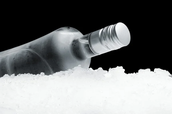 Bottle of vodka lying on ice on black background — Stock Photo, Image