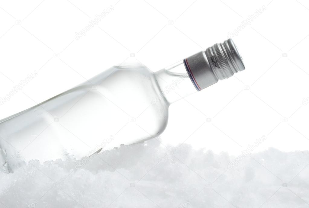 Bottle of vodka lying on ice on white background