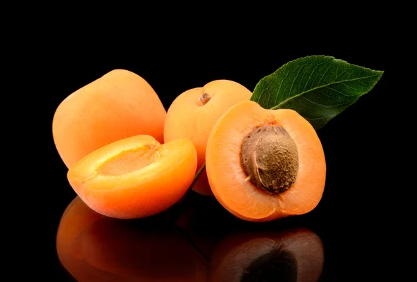 Три нарезанных абрикоса, изолированных на черном — стоковое фото
