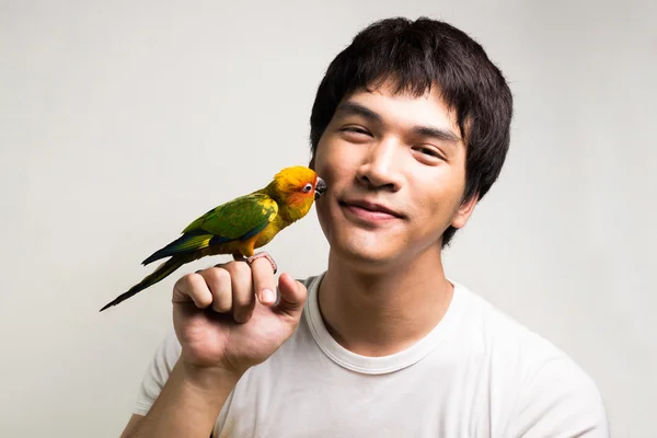 Asiatiska män med papegoja - solen conure — Stockfoto