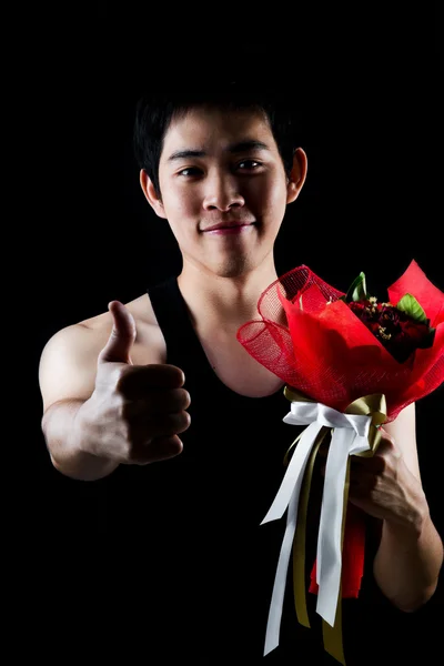 Asiatico ragazzo con rosso bouquet in scuro sfondo — Foto Stock