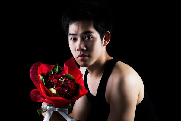 Aziatisch jongen met rood boeket in donkere achtergrond — Stockfoto