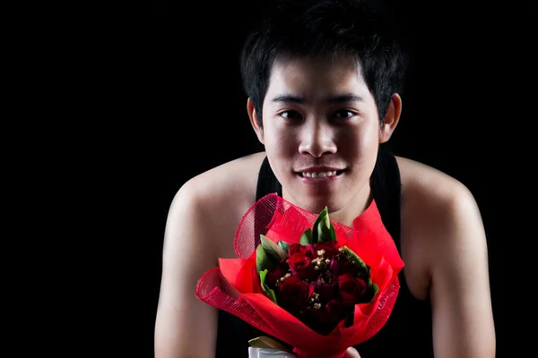 Asiatischer Junge mit rotem Strauß vor dunklem Hintergrund — Stockfoto