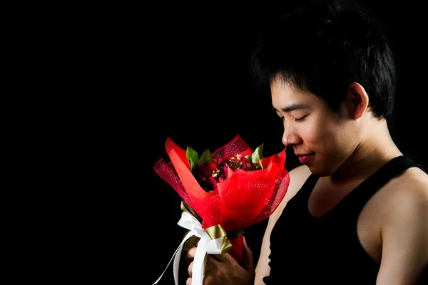 Asian boy with red bouquet in dark background — Stock Photo, Image