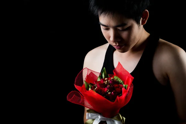 Asiático chico con rojo ramo en oscuro fondo — Foto de Stock