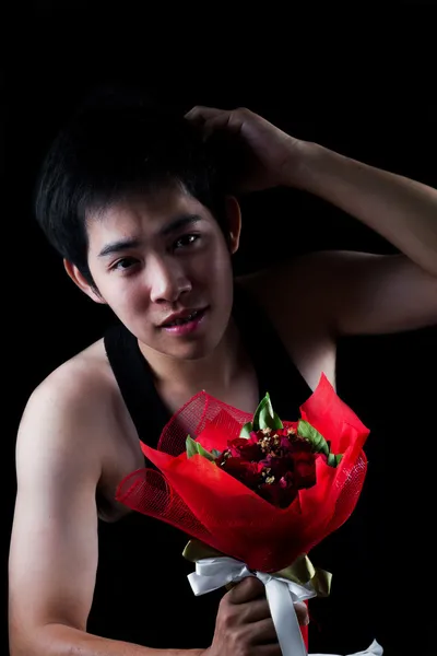 Asiatico ragazzo con rosso bouquet in scuro sfondo — Foto Stock