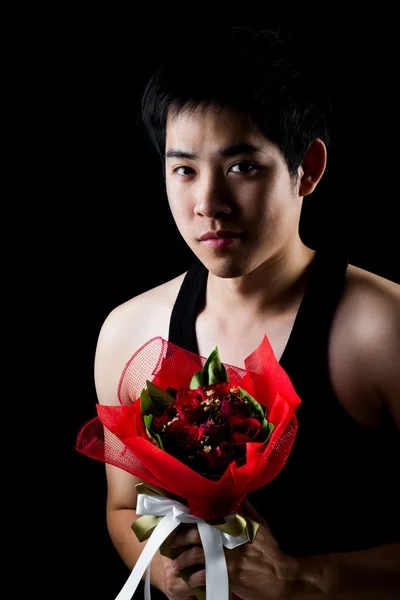 Asiático chico con rojo ramo en oscuro fondo — Foto de Stock