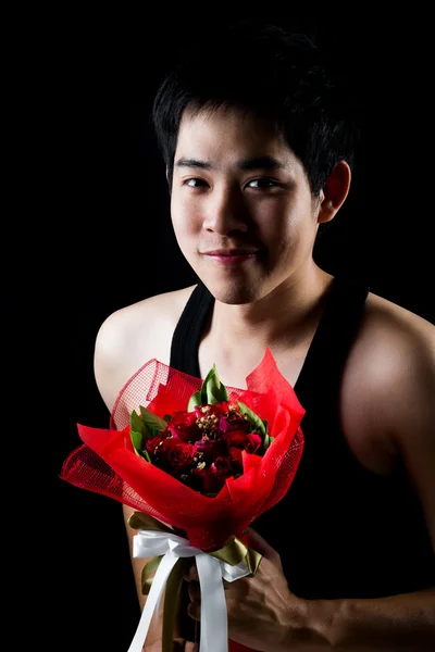 Aziatisch jongen met rood boeket in donkere achtergrond — Stockfoto