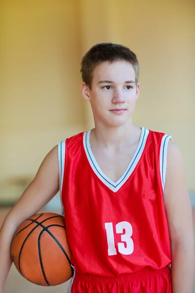 球在他的手，红色的制服的篮球运动员。在健身房里练习打篮球 — 图库照片