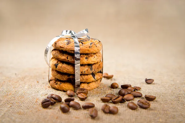 Biscuits, cinnamon sticks and coffee beans lying on sackcloth — Stock Photo, Image