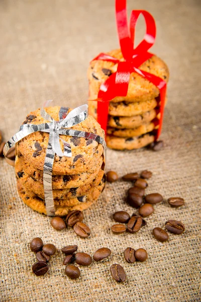 Biscuits, cinnamon sticks and coffee beans lying on sackcloth — Stock Photo, Image