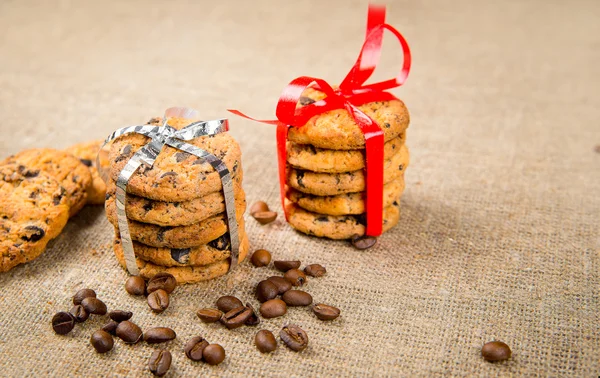 Biscuits, cinnamon sticks and coffee beans lying on sackcloth — Stock Photo, Image