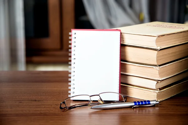 Anteckningsbok, en trave böcker, glasögon och penna — Stockfoto