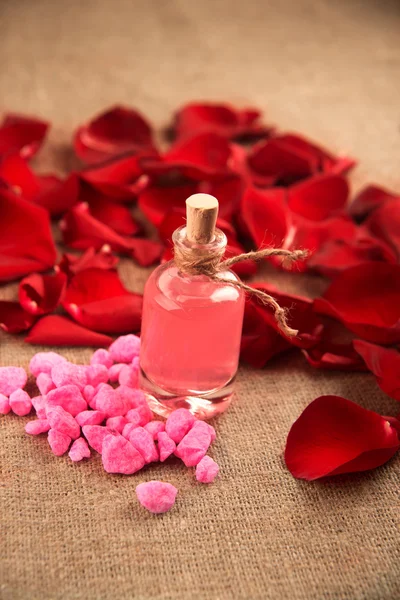 Eteerinen öljy pullo ja punaisia ruusuja, hajuvettä — kuvapankkivalokuva